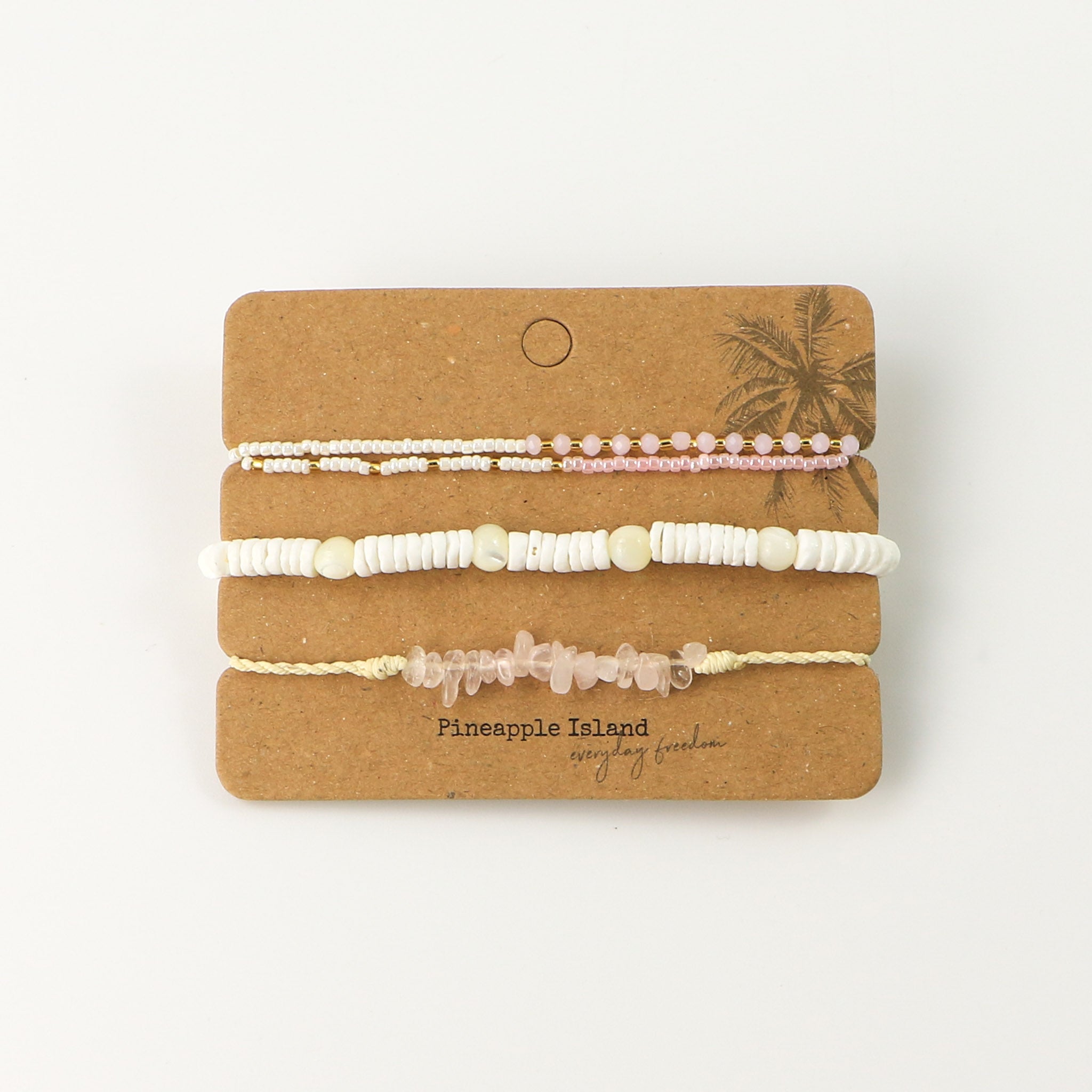 Our limited edition Galentines (Valentines) bracelet set pictured on a white background. A white, pink and gold double layer beaded bracelet, a white puka shell and shimmering troca shell bead bracelet, and our Love Is Here rose quartz gemstone bracelet.