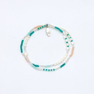 Multi-strand beaded bracelet with turquoise, white, and beige beads on a white background