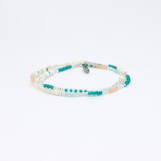Multi-strand beaded bracelet with turquoise, white, and beige beads on a white background