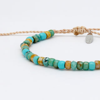 Close up of a beaded bracelet with turquoise and yellow beads on a white background