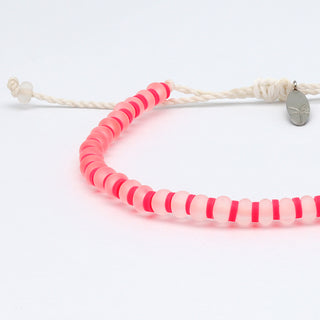 Close up of a bright pink bracelet on a white background