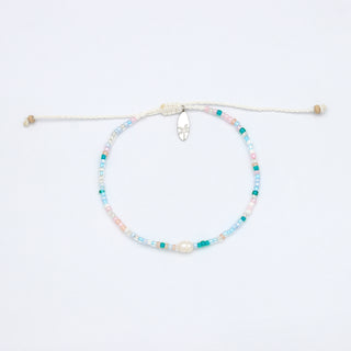 Beaded pastel colour bracelet with a pearl in the centre, on a white background