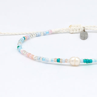 Close up of a pastel colour beaded bracelet with a pearl and a small charm on a white background
