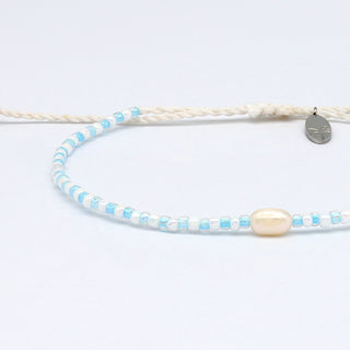 Close up of a white and light blue colour beaded bracelet with a pearl and a small charm on a white background