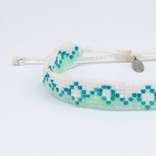Close up of beaded bracelet with white and blue mountain pattern on a white background