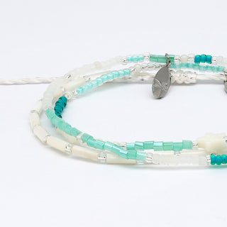 close up of two beaded bracelets with turquoise and white beads on a white background