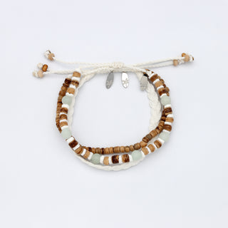 Set of three bracelets made with wood, shell, stone and braided cord on a white background