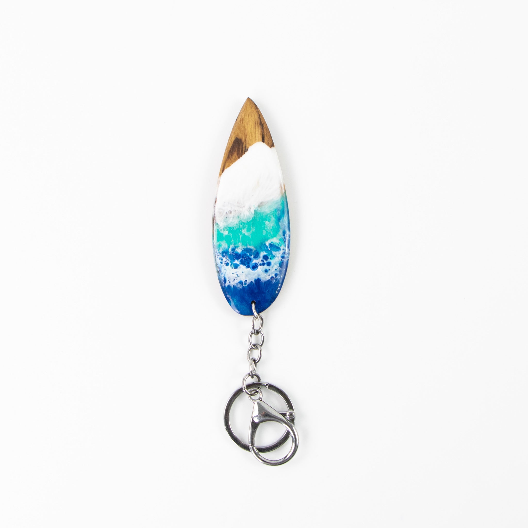 Wooden surfboard shaped keyring with resin blue and white wave design, on white back ground